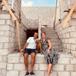 Lize met haar man en hond Chabo bij een muur in Willemstad.
